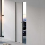 Puerta corredera rasomuro Scrigno Openbox integrada en la pared, con diseño minimalista sin marcos visibles que permite una apertura discreta y un acabado limpio y moderno.