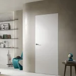 Puerta rasomuro Scrigno Filo44 en acabado blanco, integrada en la pared sin marcos ni molduras, con diseño minimalista que aporta continuidad visual y un estilo moderno y elegante al espacio.