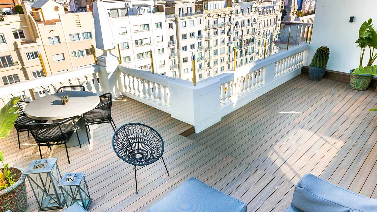 Terraza urbana con tarima de exterior tecnológica con veta texturizada, amueblada con sofá y comedor de exterior, ideal para espacios modernos.