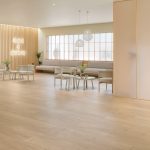 Suelo laminado Finfloor Evolve en estancia moderna y luminosa, acabado roble claro con alta resistencia al desgaste y al agua, ideal para espacios elegantes y de uso intensivo.