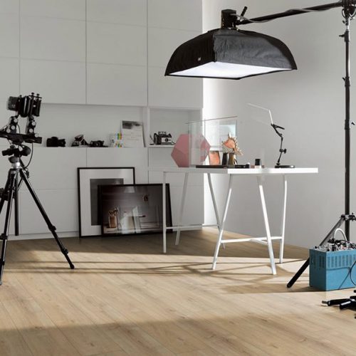 Interior de estudio fotográfico moderno con suelo laminado Parador Trendtime 6 AC5 en tono roble claro, donde se aprecian lamas amplias con veta natural que aportan luminosidad, calidez y un estilo contemporáneo al espacio.