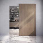 Guía oculta Palbox CoverUp para puerta corredera de madera con cierre suave, instalada en pared sin carril visible.